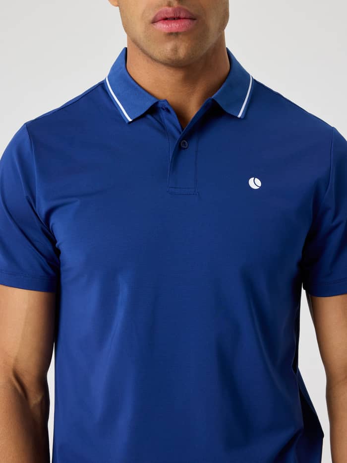 Front close-up of a man wearing the Björn Borg Ace Polo Shirt in Blue Depths (Blue) with a white tennis ball logo.