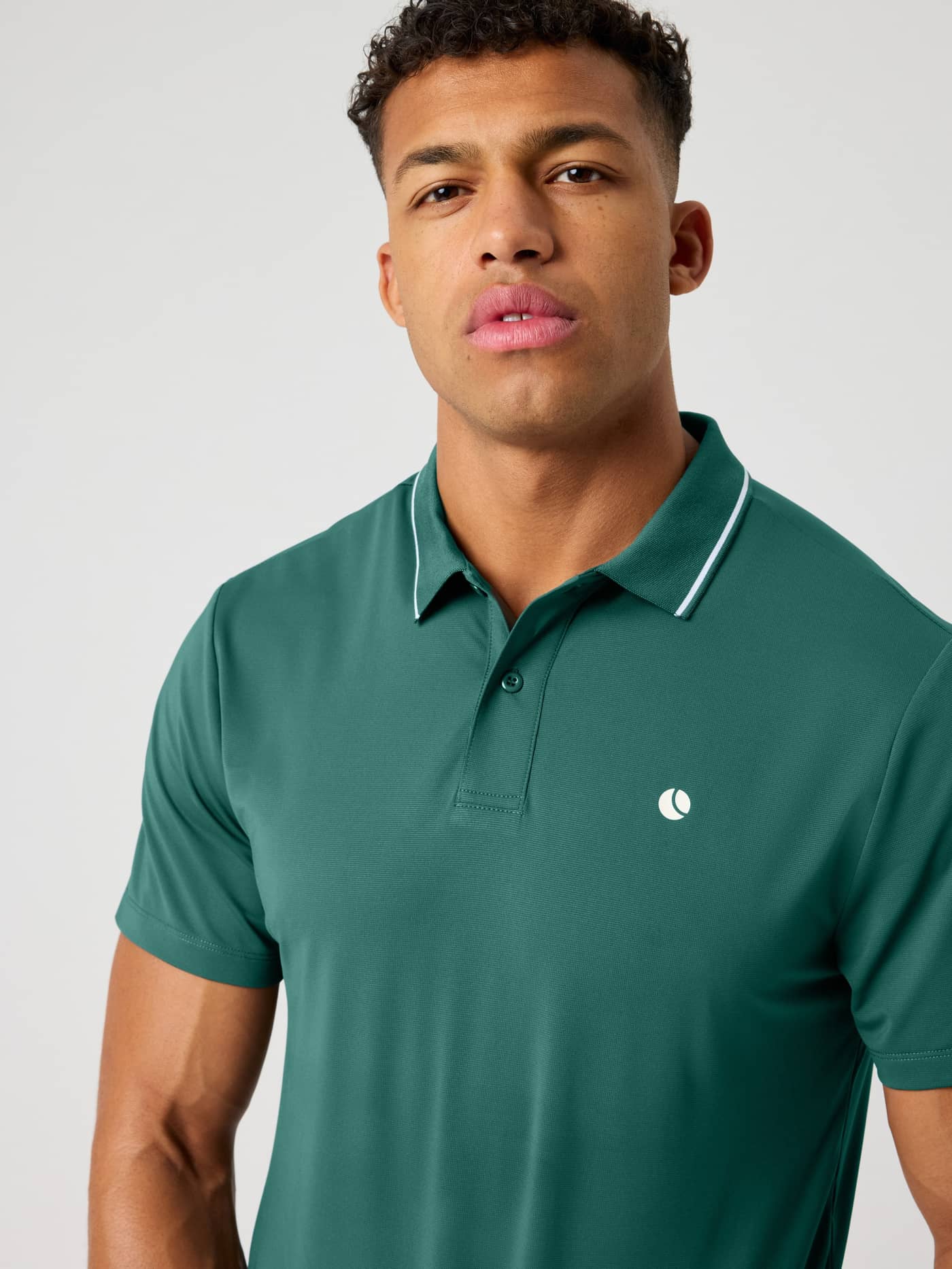 Front close-up of the Ace Polo Shirt in Mallard Green (Green) featuring a white tennis ball logo for tennis and padel. - Image 1
