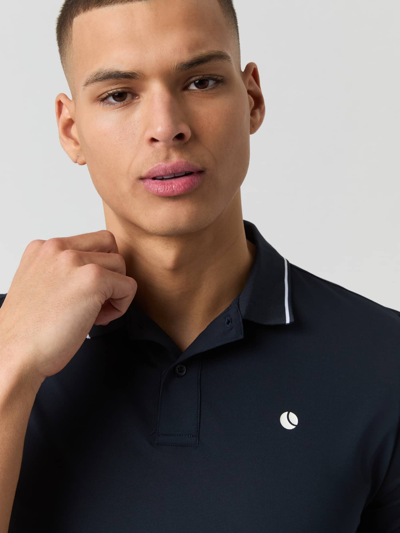 Närbild på Ace Polo Shirt i Night sky (Marinblå) för tennis med fokus på kragen och vit bröstlogotyp. - Image 5