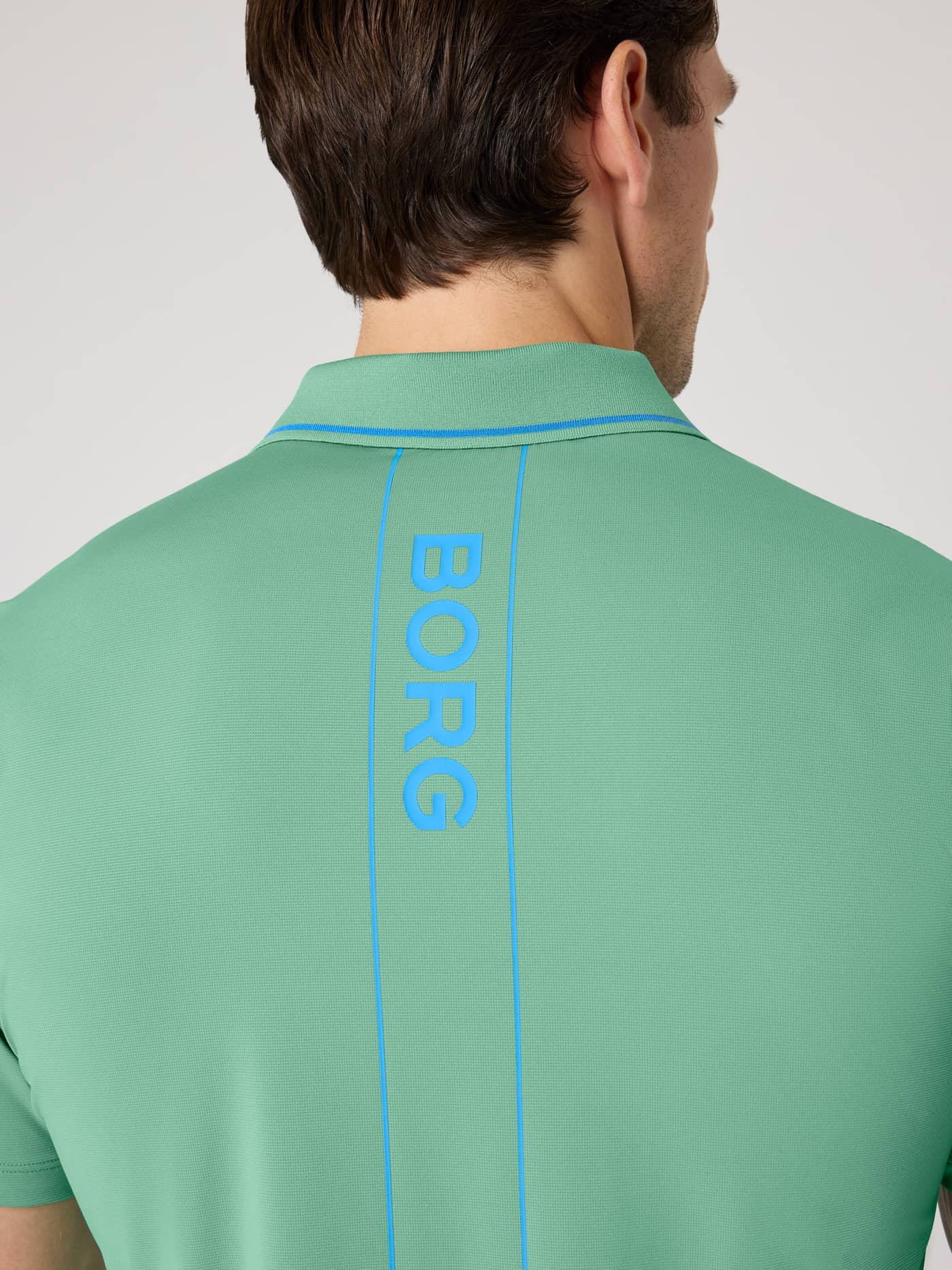 Close-up back view of the performance Ace Polo Shirt in Malachite Green (Green) for tennis, with a blue BORG logo stripe. - Image 4