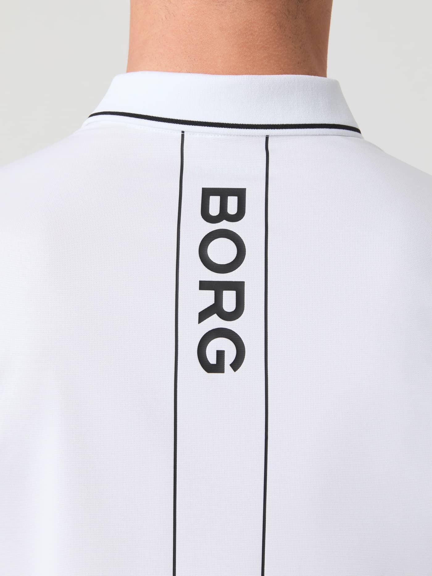 Nærbillede af Ace Polo Shirt i Brilliant White (Hvid) set bagfra med vertikal BORG-logostribe til tennis. - Image 6