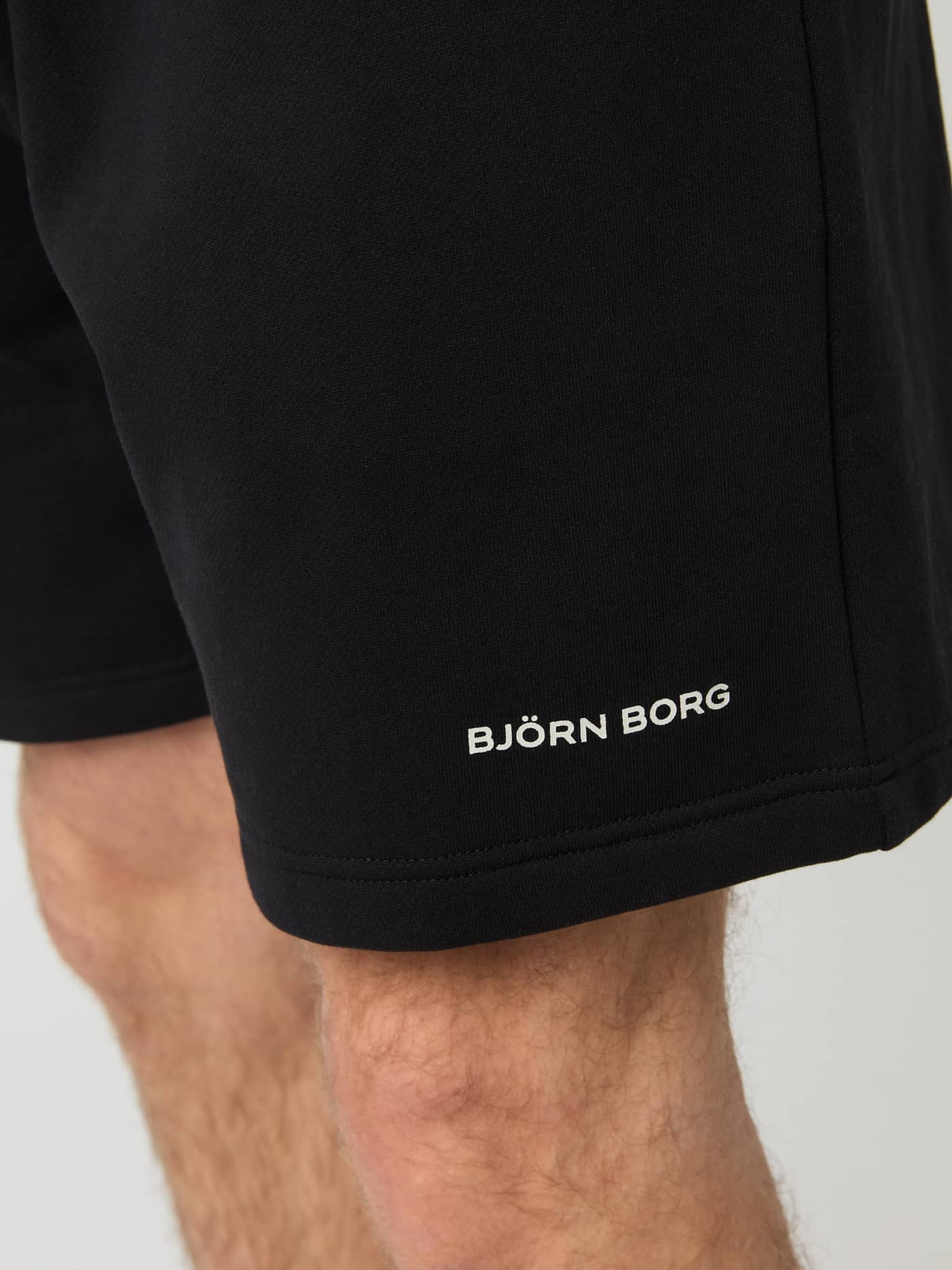 Detailed close-up of the white logo on the heavy-quality fleece Borg Oversized Sweatshorts in Black Beauty (Black). - Image 4