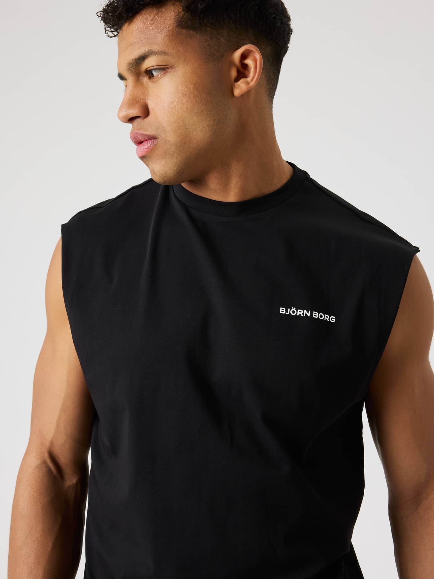 Front view of a man in a training Borg Gym Sleeveless T-Shirt in Black Beauty (Black) with an oversized fit and white logo. - Image 5