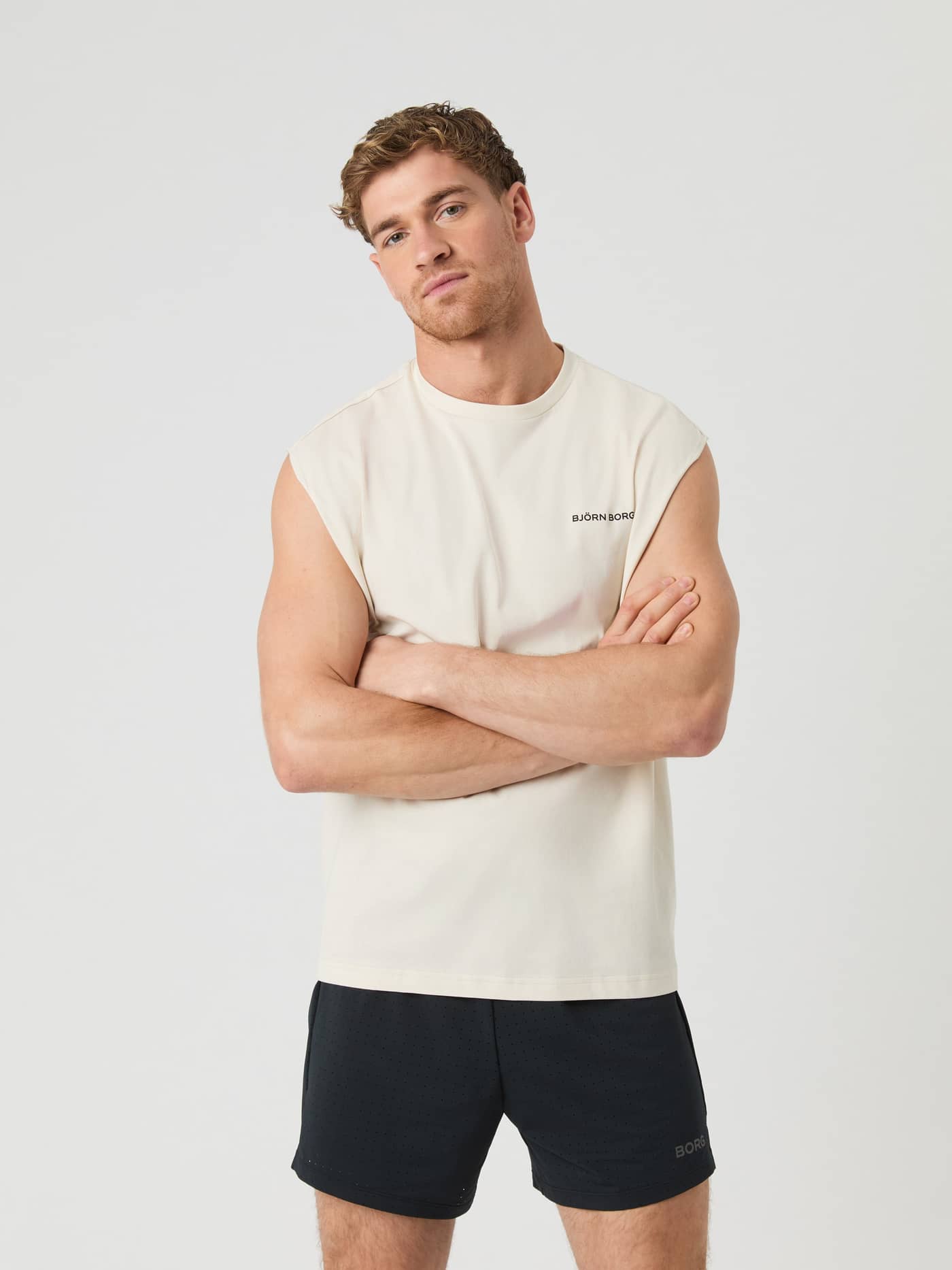 Front view of a man in the cotton-blend Birch (White) Borg Gym Sleeveless T-Shirt with a black logo, ideal for gym training. - Image 1
