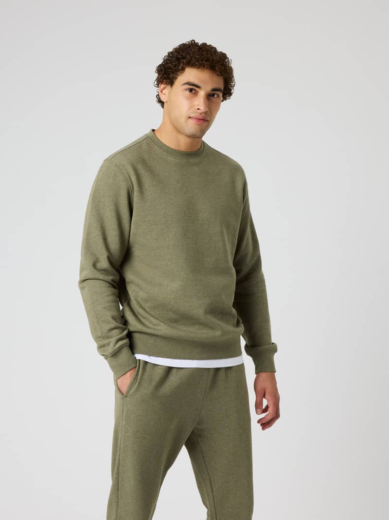 Front view of a man wearing the Centre Sweatshirt in Winter Moss Melange (Green) with a regular fit and soft melange texture.