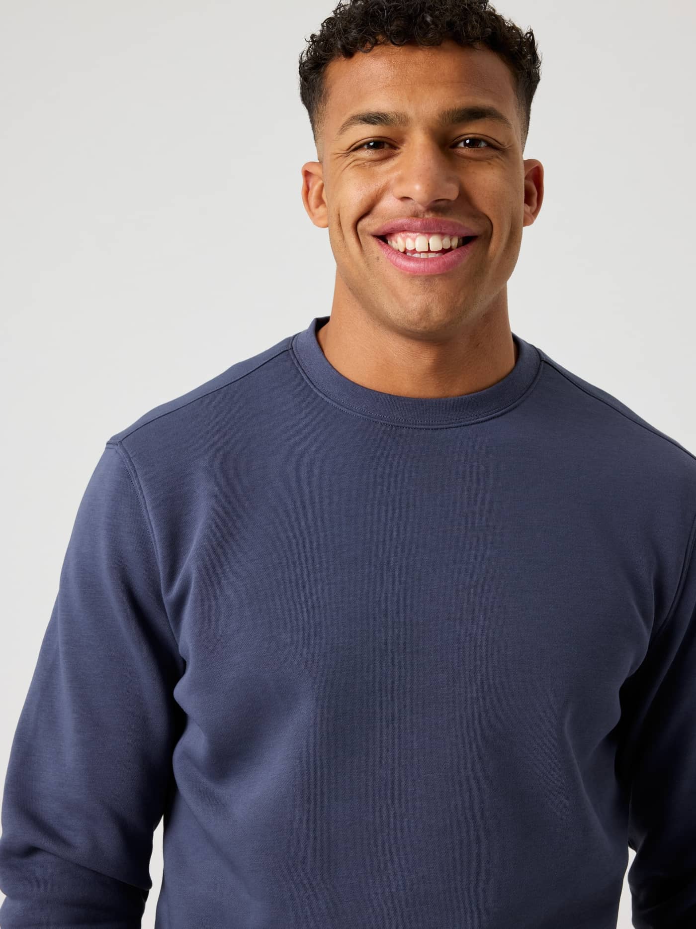 Gros plan de face d'un homme portant le Centre Sweatshirt en Odyssey Gray (bleu), alliant style et fonction. - Image 4