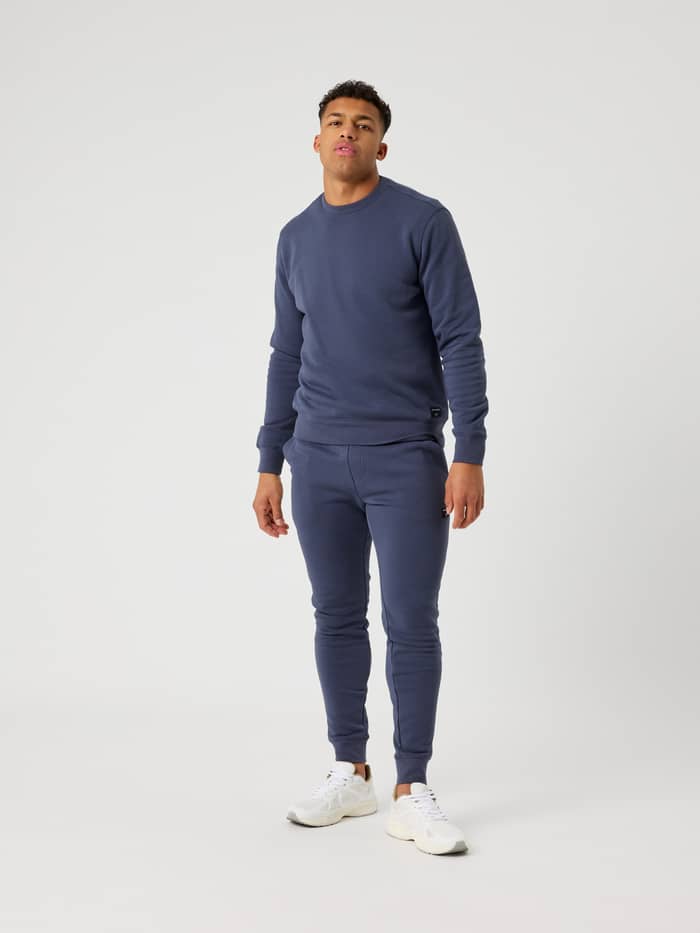 Full-body front view of a man wearing the regular fit Björn Borg Centre Sweatshirt in Odyssey Gray (Blue) and matching pants. - Image 3