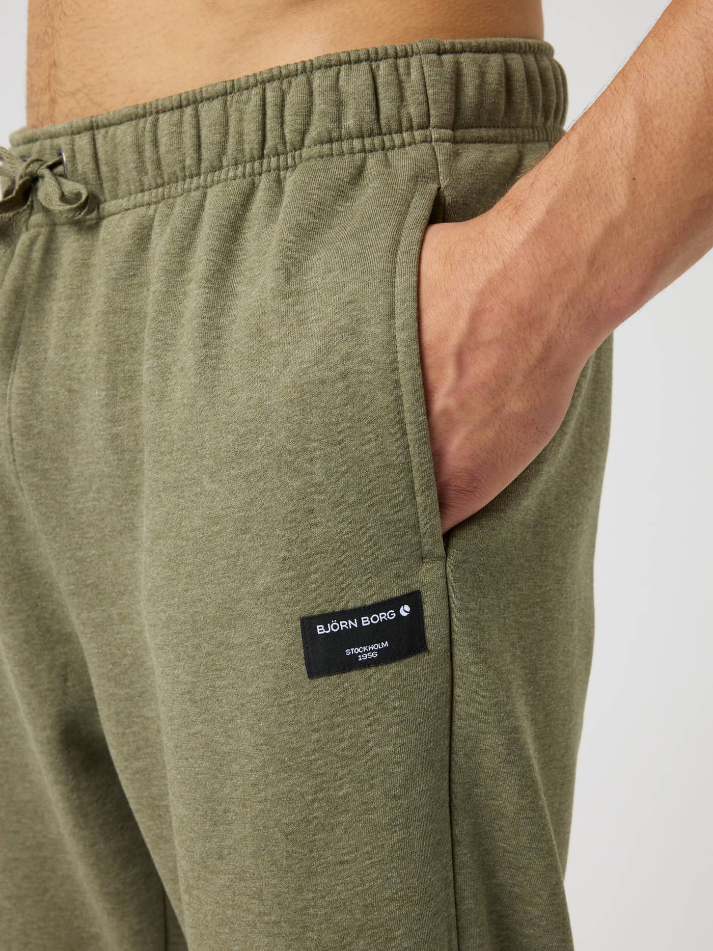 Close-up of the Björn Borg Centre Sweatpants in Winter Moss Melange (Green) with a black logo label. - Image 4