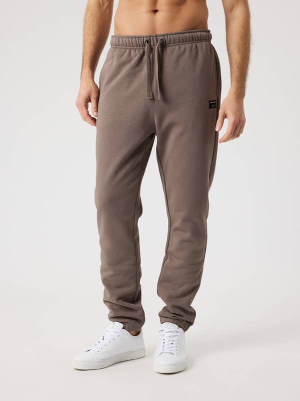 Front view of a man wearing the Björn Borg Centre Sweatpants in Falcon (Brown) with a black logo and drawstring waist.
