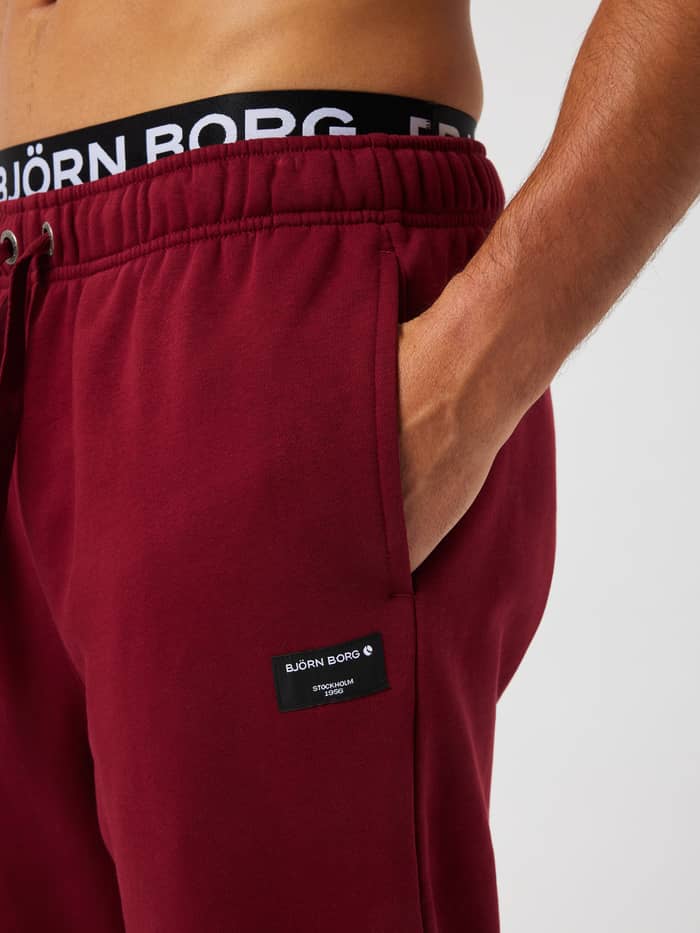 Close-up of the Centre Sweatpants in Cabernet (Red) highlighting the side pocket and woven logo label.