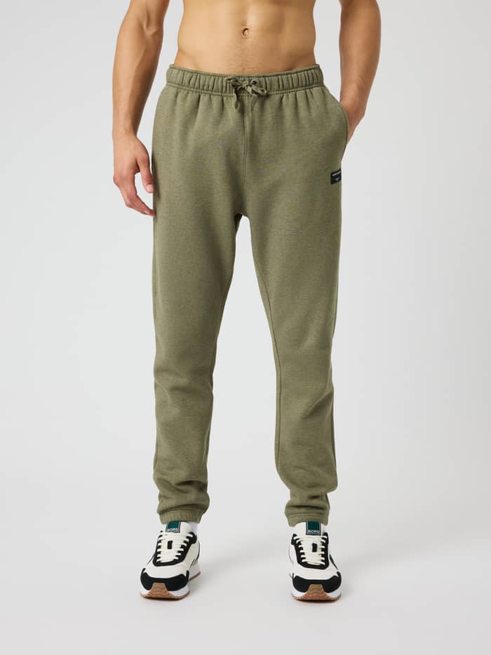 Front view of a man wearing Centre Sweatpants in Winter Moss Melange (Green) with a drawstring and black logo label.