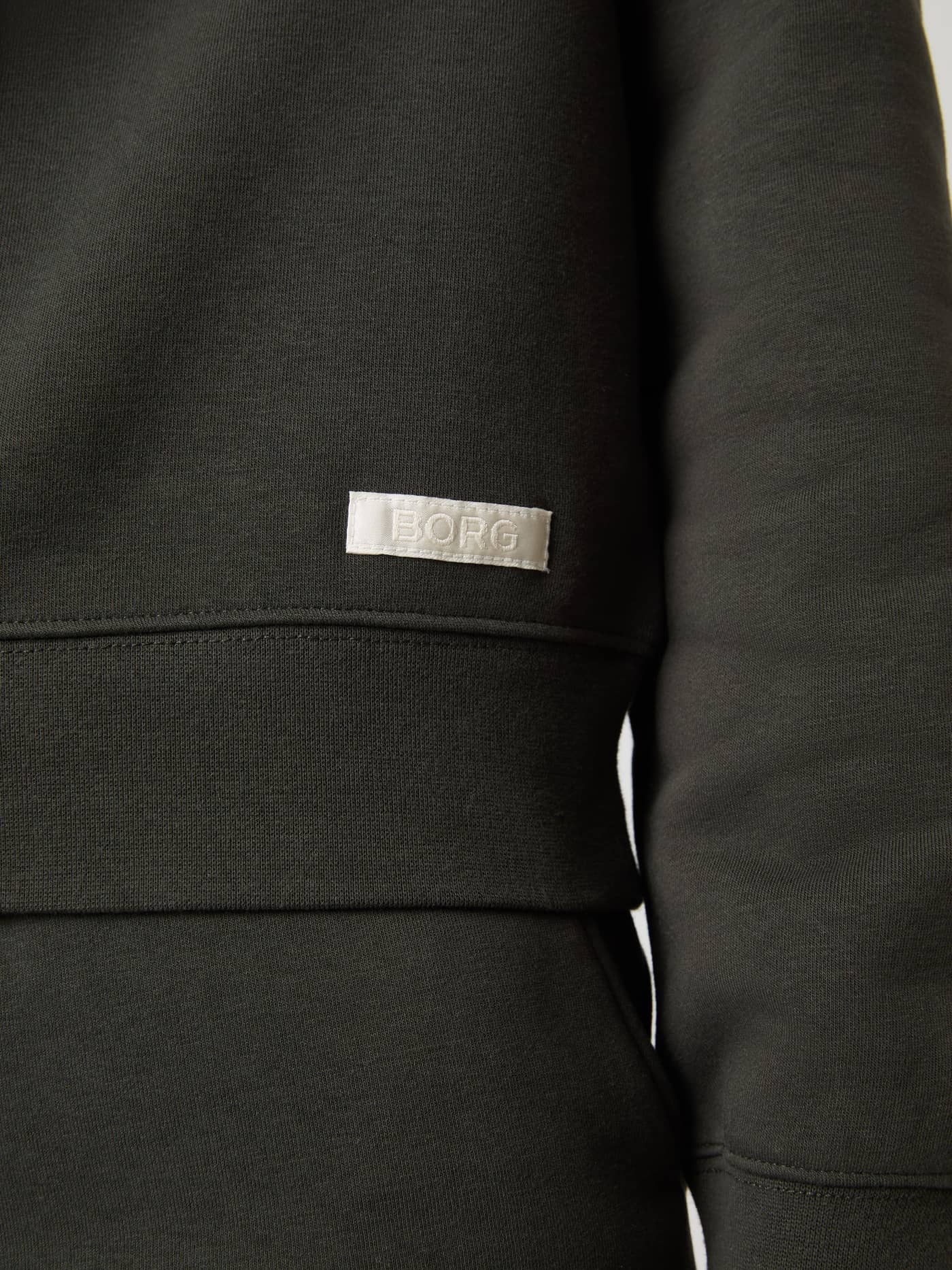 Närbild på mjuk Centre Sweatshirt för dam i Peat (Grön) med vit vävd logoetikett och ribbad fåll. - Image 5