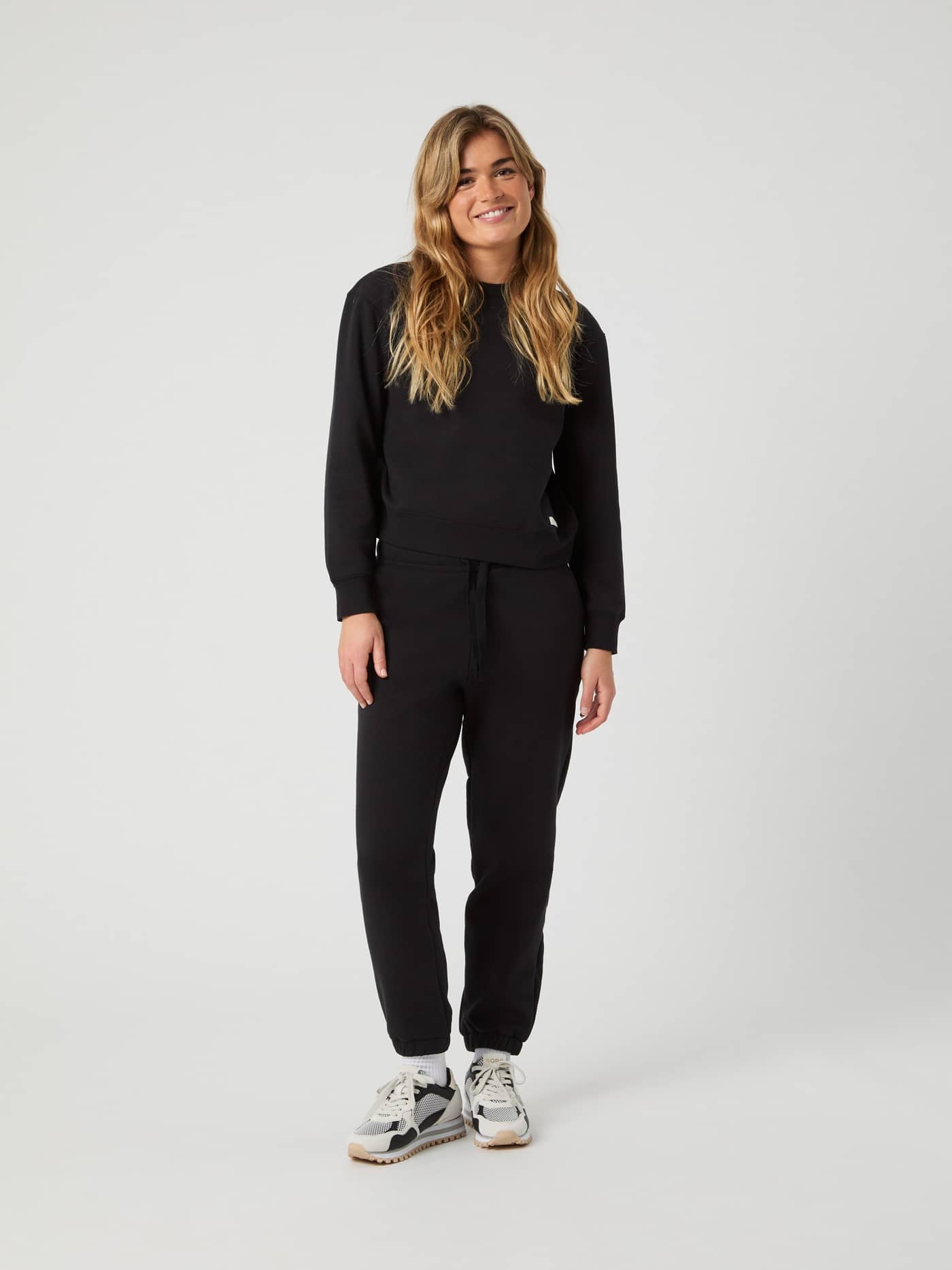Full-body front view of a woman in regular fit Björn Borg Centre Sweatshirt in Black Beauty (Black) with matching joggers. - Image 3