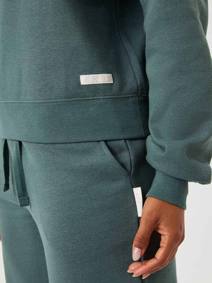Nahaufnahme des Centre Sweatshirt in Balsam Green (Grün) mit dem weißen gewebten Logo-Etikett. - Image 5