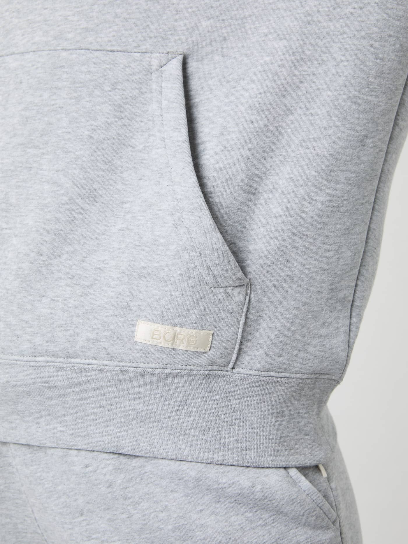 Close-up of the kangaroo pocket and off-white logo label on the soft Björn Borg Centre Hoodie in Light Grey Melange (Grey). - Image 5