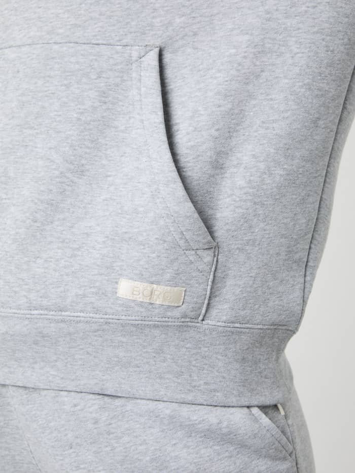 Nærbillede af kængurulommen og det råhvide logomærke på Björn Borg Centre Hoodie i Light Grey Melange (Grå). - Image 5