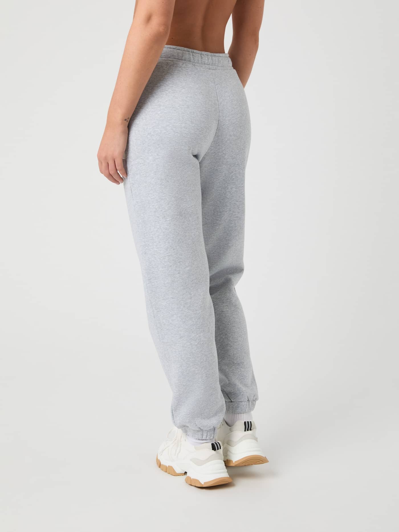Back view of a woman in the regular fit Centre Sweatpants in Light Grey Melange (Grey), featuring soft brushed fleece. - Image 3