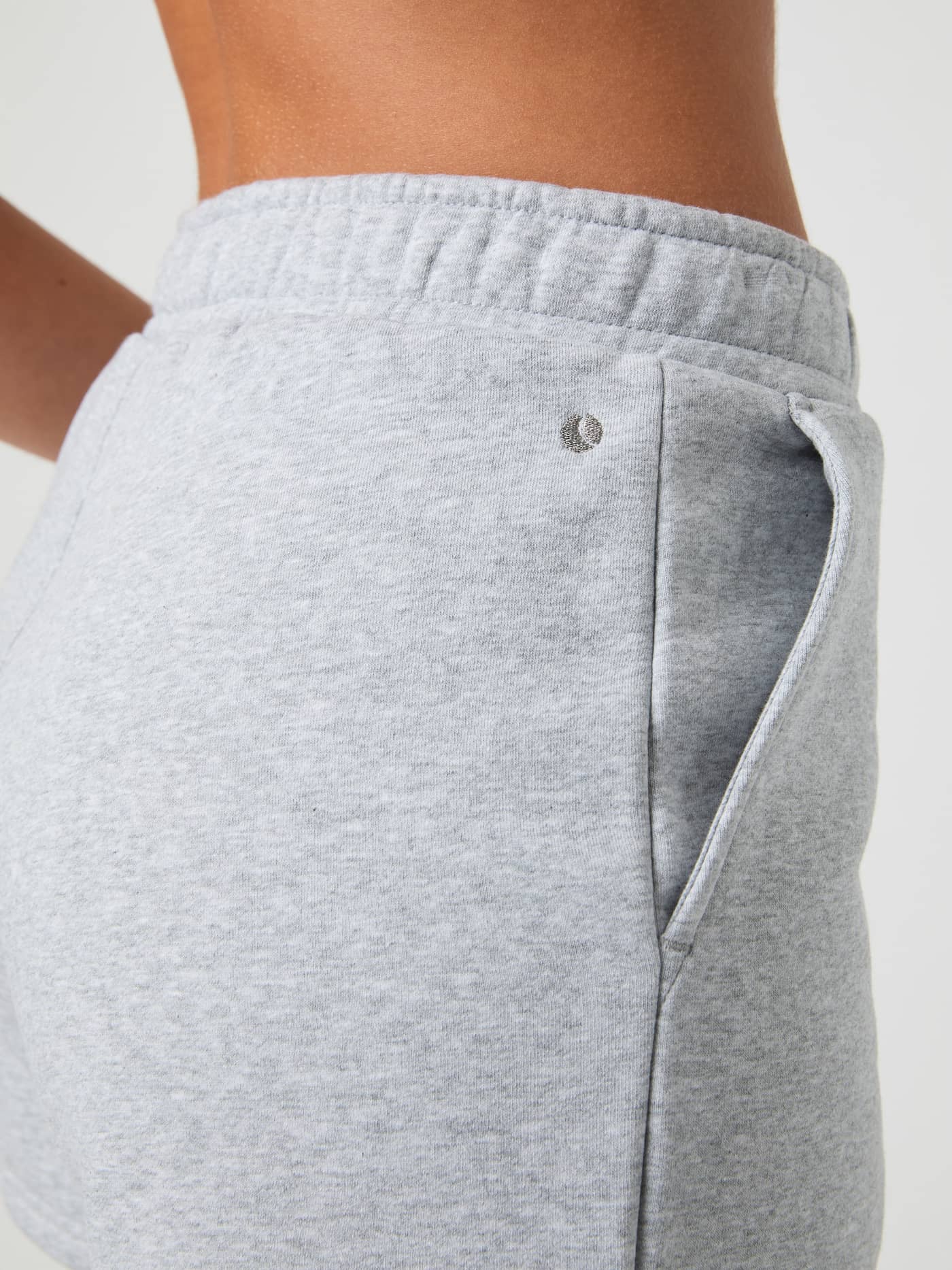 Side close-up of a woman wearing the soft Björn Borg Centre Sweatshorts in Light Grey Melange (Grey), showing the pocket. - Image 4