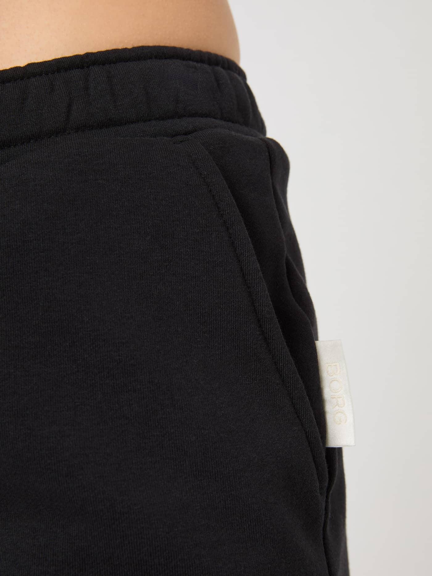 Gros plan détaillé du Centre Sweatshorts pour femme en Black Beauty (Noir) avec poche et étiquette BORG blanche. - Image 4