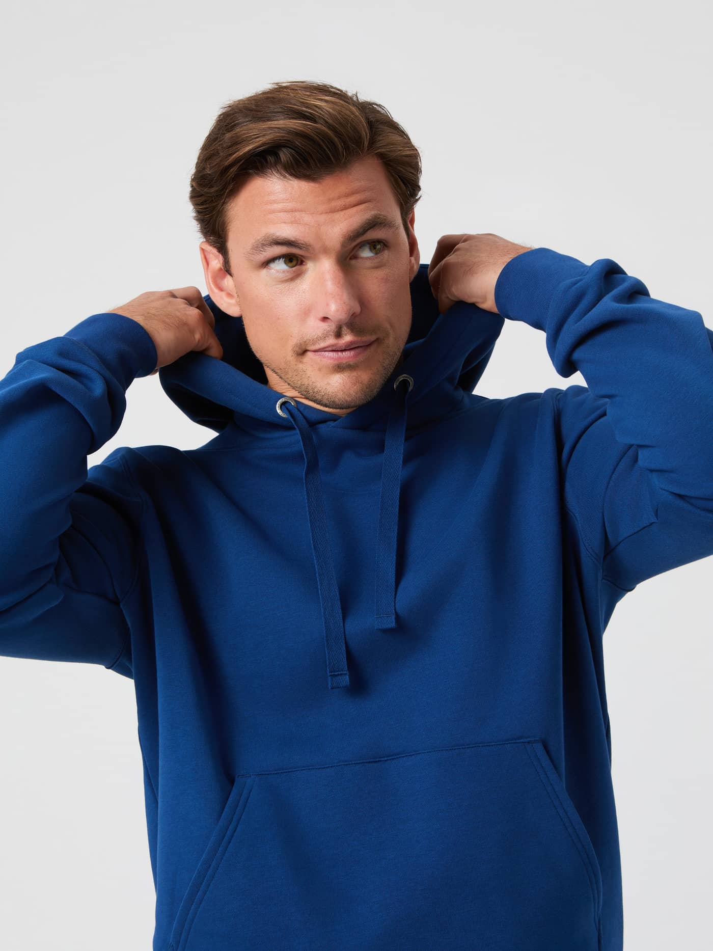 Close-up of a model wearing the Björn Borg Centre Hoodie in Estate Blue, adjusting the hood. - Image 1
