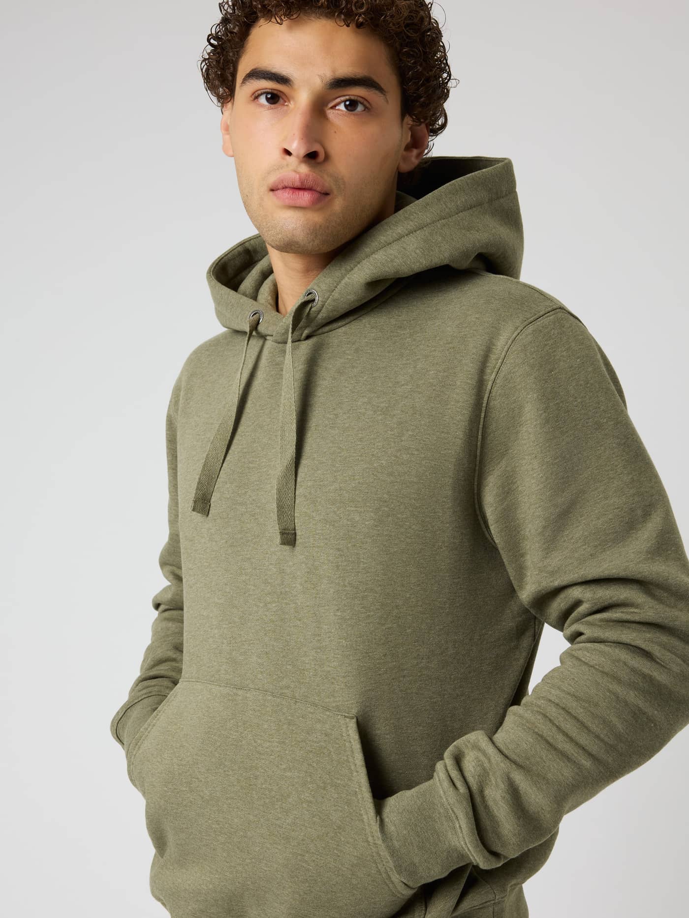Front view of a model wearing the Centre Hoodie in Winter Moss Melange (Green) with a double layer hood and kangaroo pocket. - Image 1