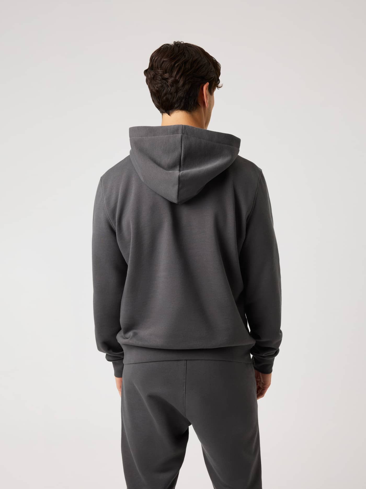 Back view of a man wearing the Centre Hoodie in Asphalt (Grey), a soft, regular-fit hoodie for premium everyday comfort. - Image 2