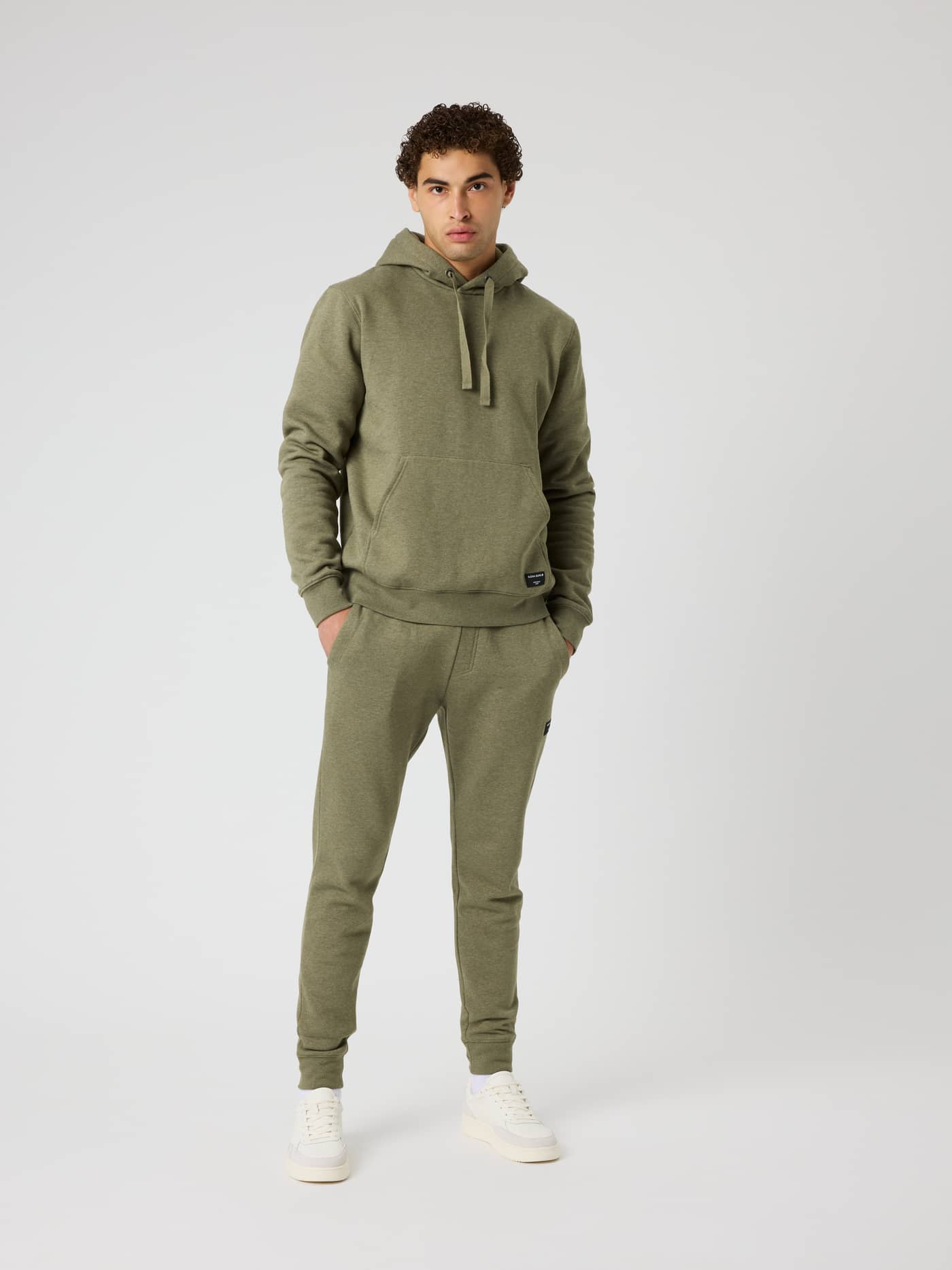 Full-body view of a model in the Centre Hoodie in Winter Moss Melange (Green), featuring a kangaroo pocket and regular fit. - Image 3