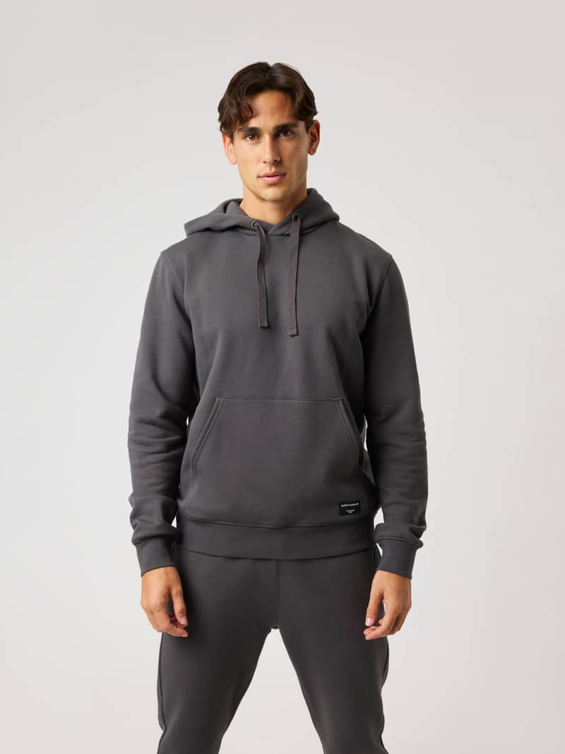 Front view of a man wearing the Björn Borg Centre Hoodie in Asphalt (Grey) with a kangaroo pocket and drawstring hood.