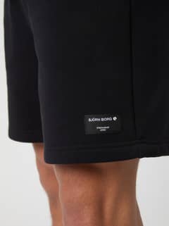 Close-up of the men's Centre Sweatshorts in Black Beauty (Black) highlighting the black logo label on the leg. - Image 4