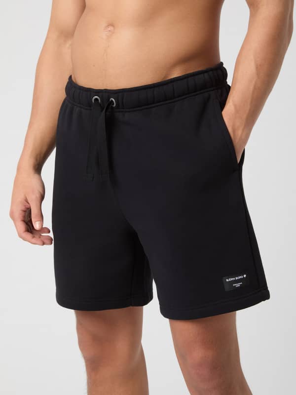 Vue de face d'un homme portant le Centre Sweatshorts en Black Beauty (Noir) avec cordon de serrage à la taille.