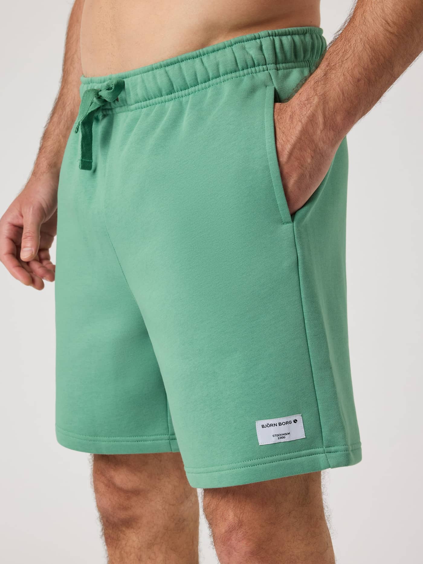 Centre Sweatshorts i Malachite Green (Grøn) med hvidt logo set fra siden med en stilfuld pasform og sidelomme. - Image 4