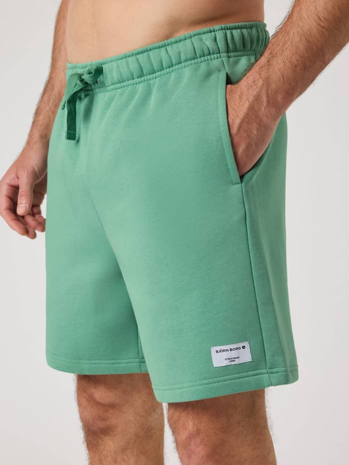Centre Sweatshorts i Malachite Green (Grøn) med hvidt logo set fra siden med en stilfuld pasform og sidelomme. - Image 4