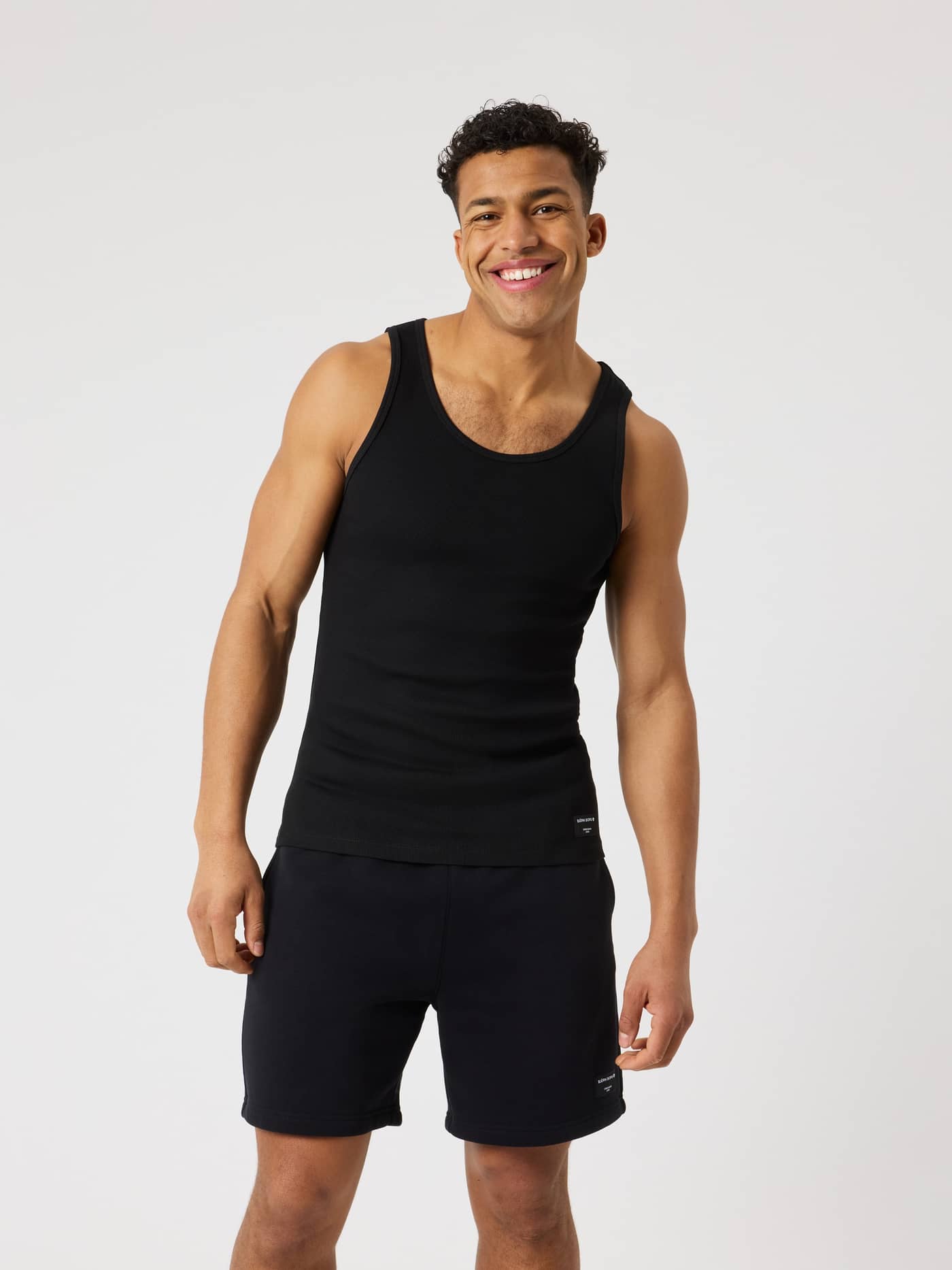 Centre Ribbed Tank i Black Beauty (Sort) set forfra på en mand i funktionelt, ribbet stof med et lille sort logo. - Image 1