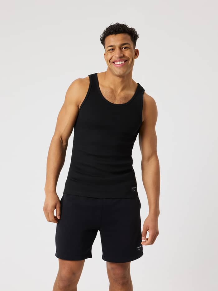 Vista frontal de hombre con Centre Ribbed Tank en Black Beauty (Negro) de suave canalé, ajuste entallado y logo negro.
