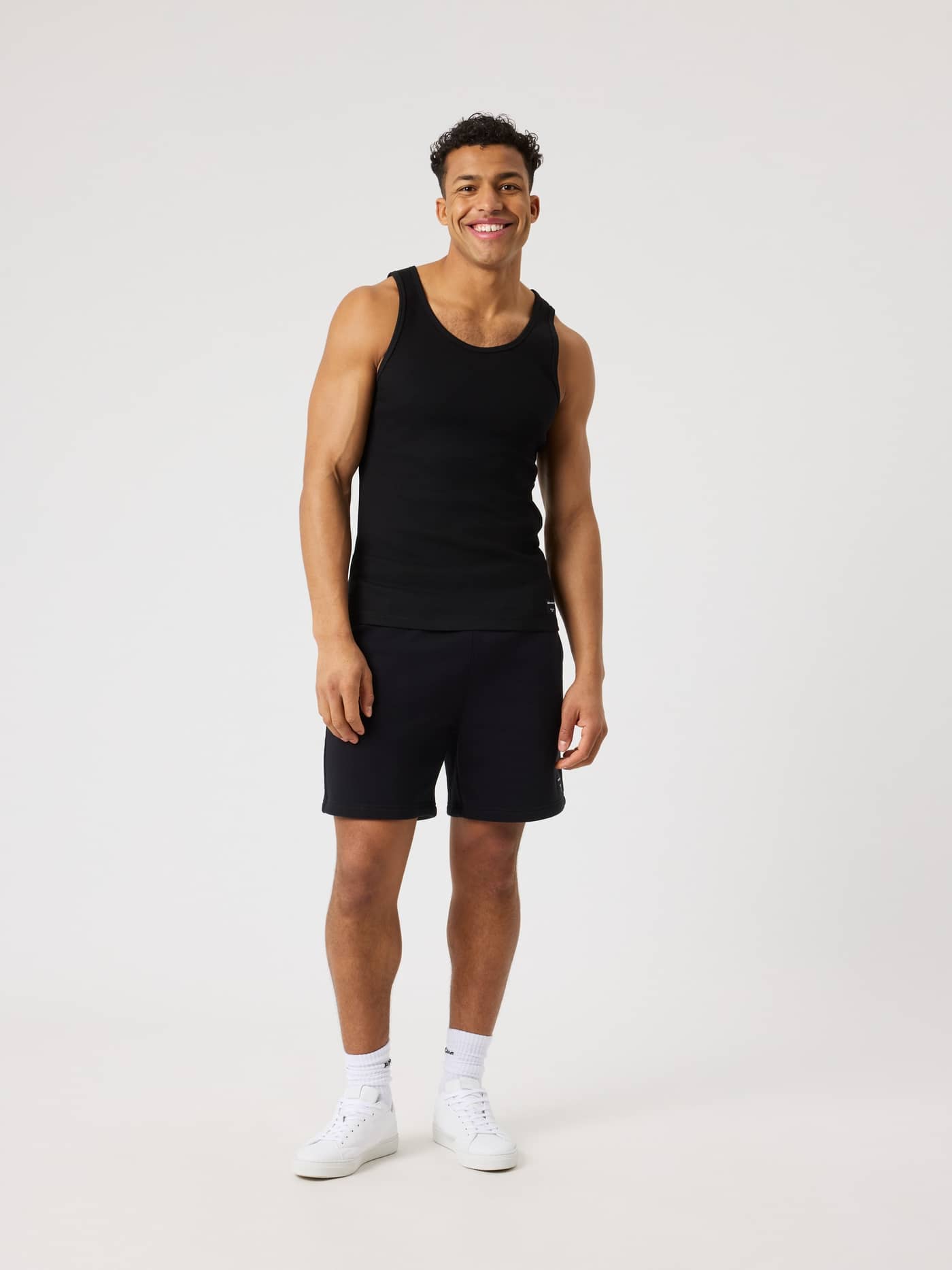 Full-body front view of a man wearing the slim-fit Björn Borg Centre Ribbed Tank in Black Beauty (Black). - Image 3