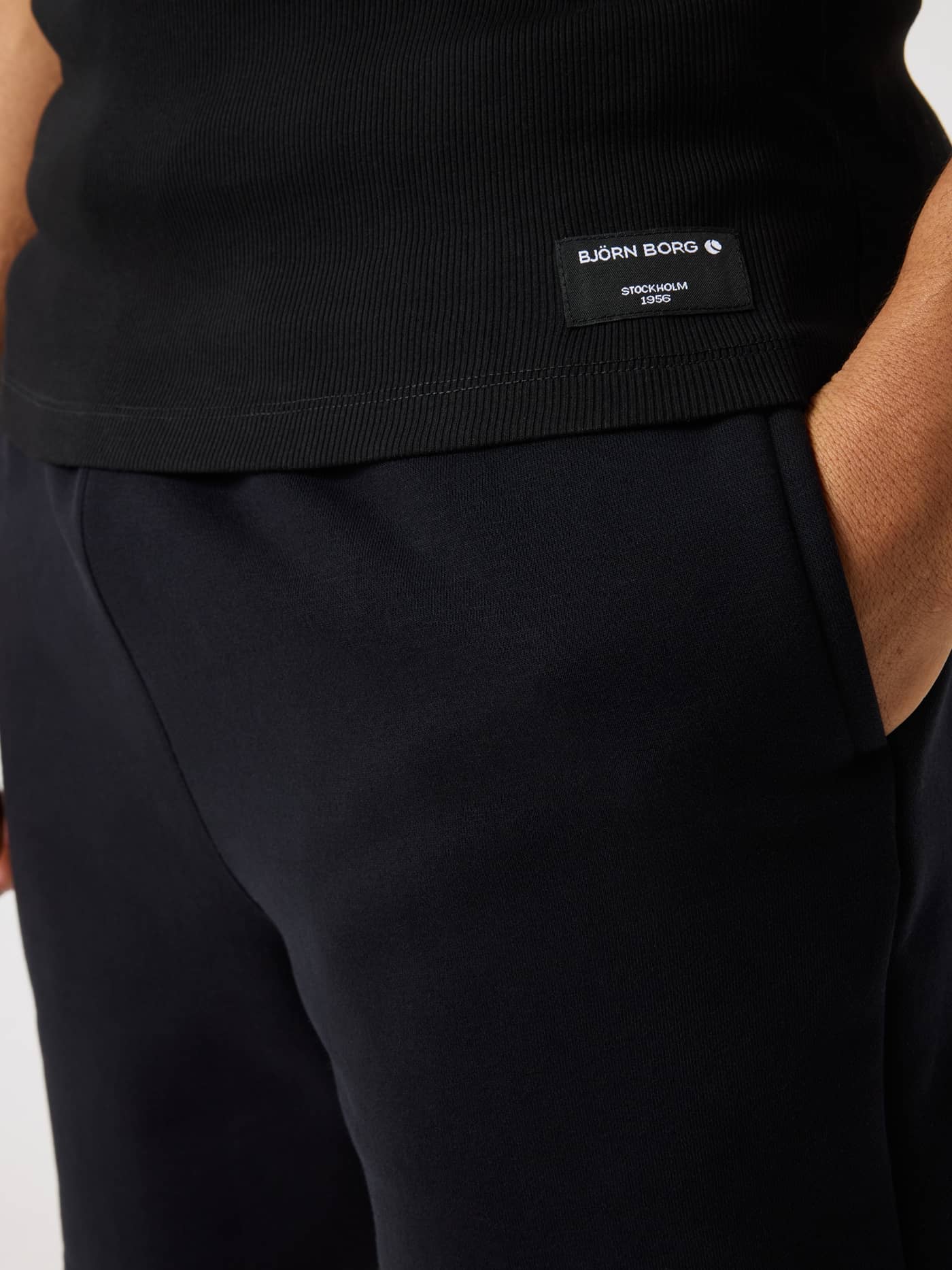 Detailed close-up of the white logo label and ribbed fabric on the Black Beauty (Black) Centre Ribbed Tank for men. - Image 4