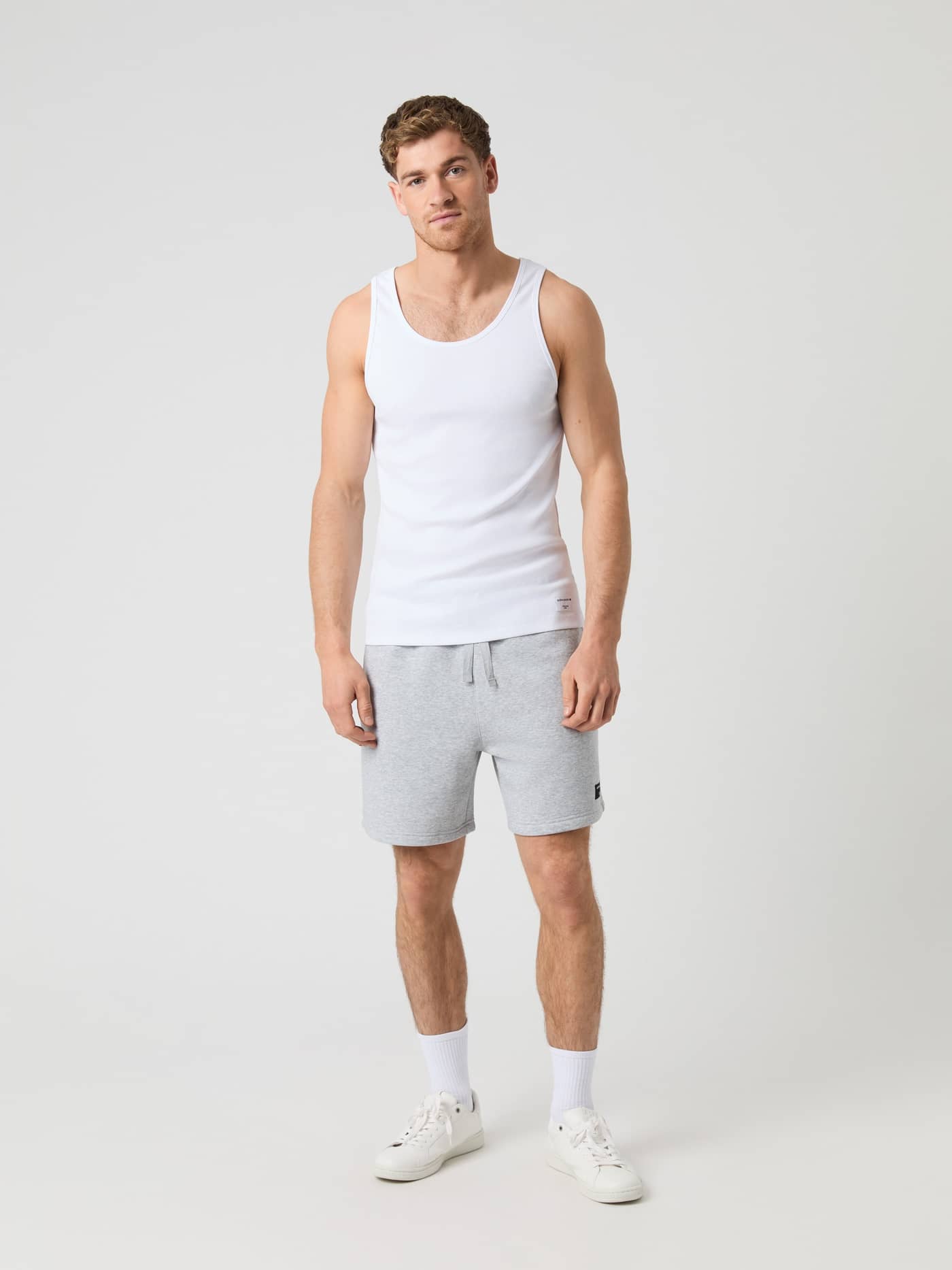 Björn Borg Centre Ribbed Tank in Brilliant White (Wit) met wit logo en grijze short, getoond in vooraanzicht op een man. - Image 3