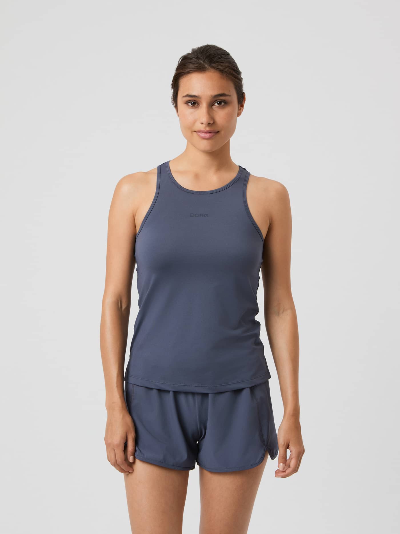 Front view of a woman wearing the Borg Racerback Tank Top in Odyssey Gray (Grey), a stylish regular fit training top. - Image 1