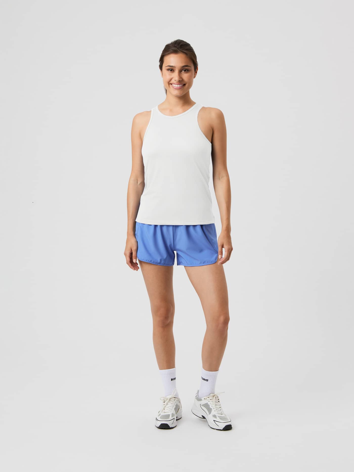 Full-body front view of a woman in the training-ready Borg Racerback Tank Top in Cannoli Cream (White), regular fit. - Image 3