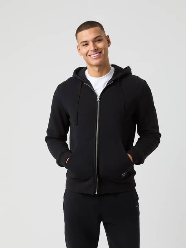 Vue de face d'un homme portant le Centre Zip Hoodie de Björn Borg en Black Beauty (Noir) avec fermeture zippée frontale.