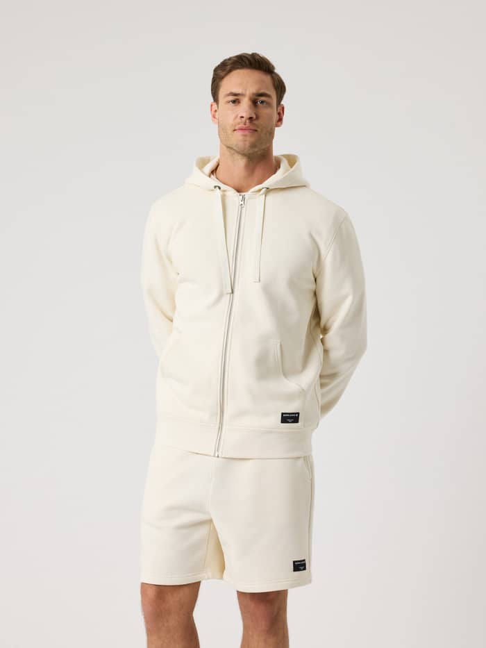 Björn Borg Centre Zip Hoodie i Tofu (Vit) sedd framifrån på en man med hel dragkedja fram och huva.