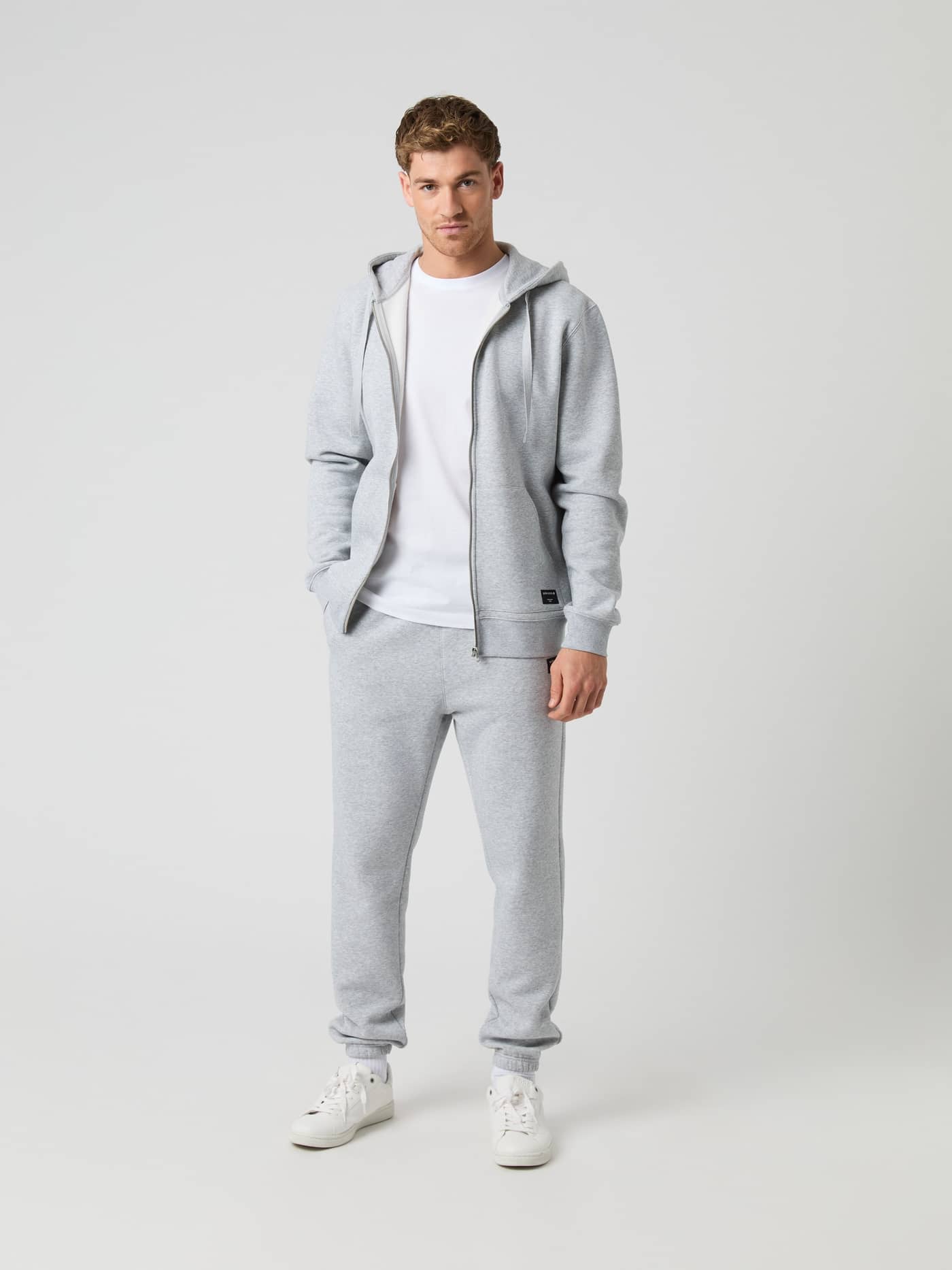 Full-body front view of a man wearing the stylish, regular fit Björn Borg Centre Zip Hoodie in Light Grey Melange (Grey). - Image 2