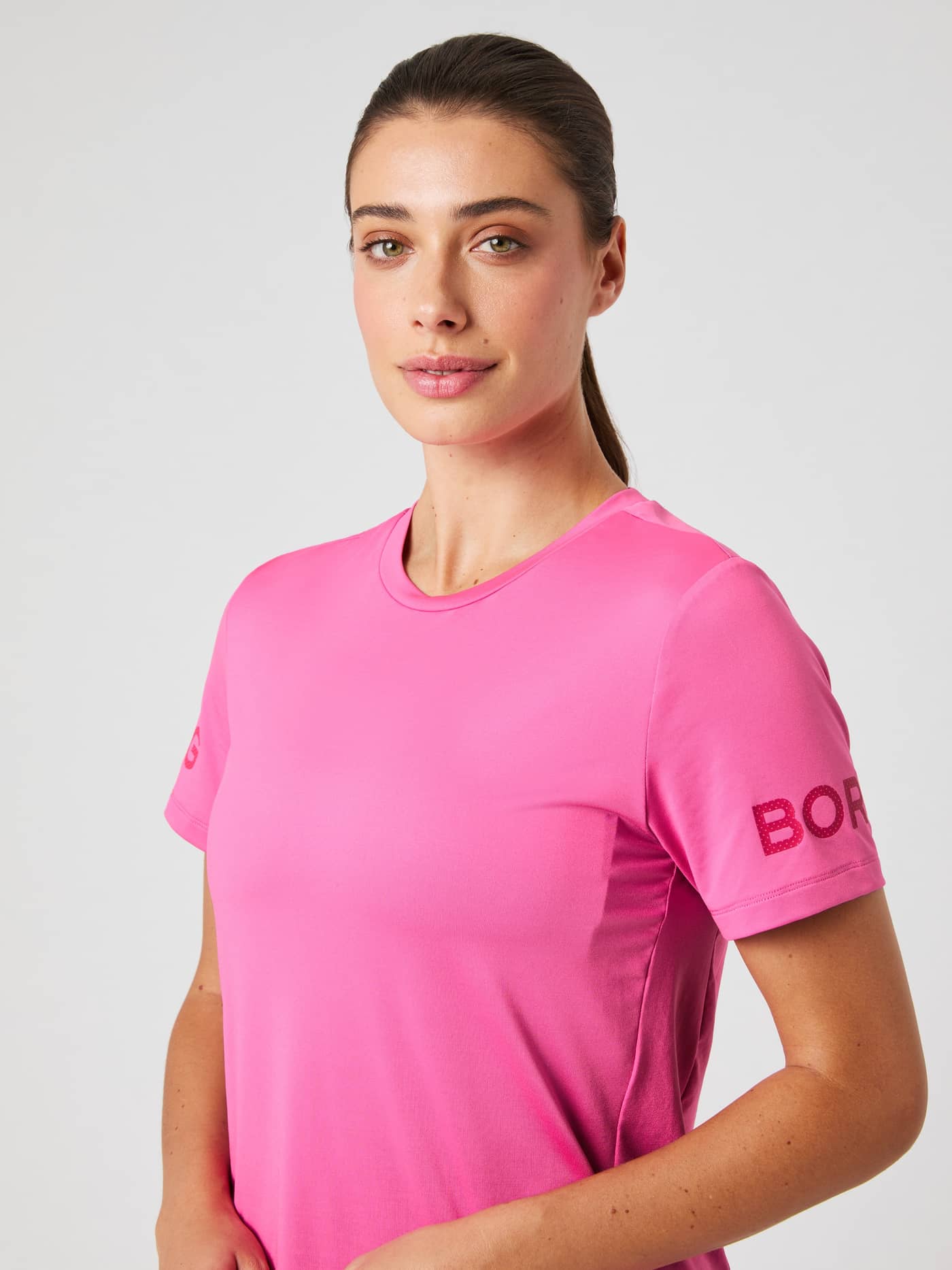 Närbild framifrån på en modell i Borg T-shirt i Ibis Rose (Rosa) för träning med logotyper på ärmarna. - Image 4