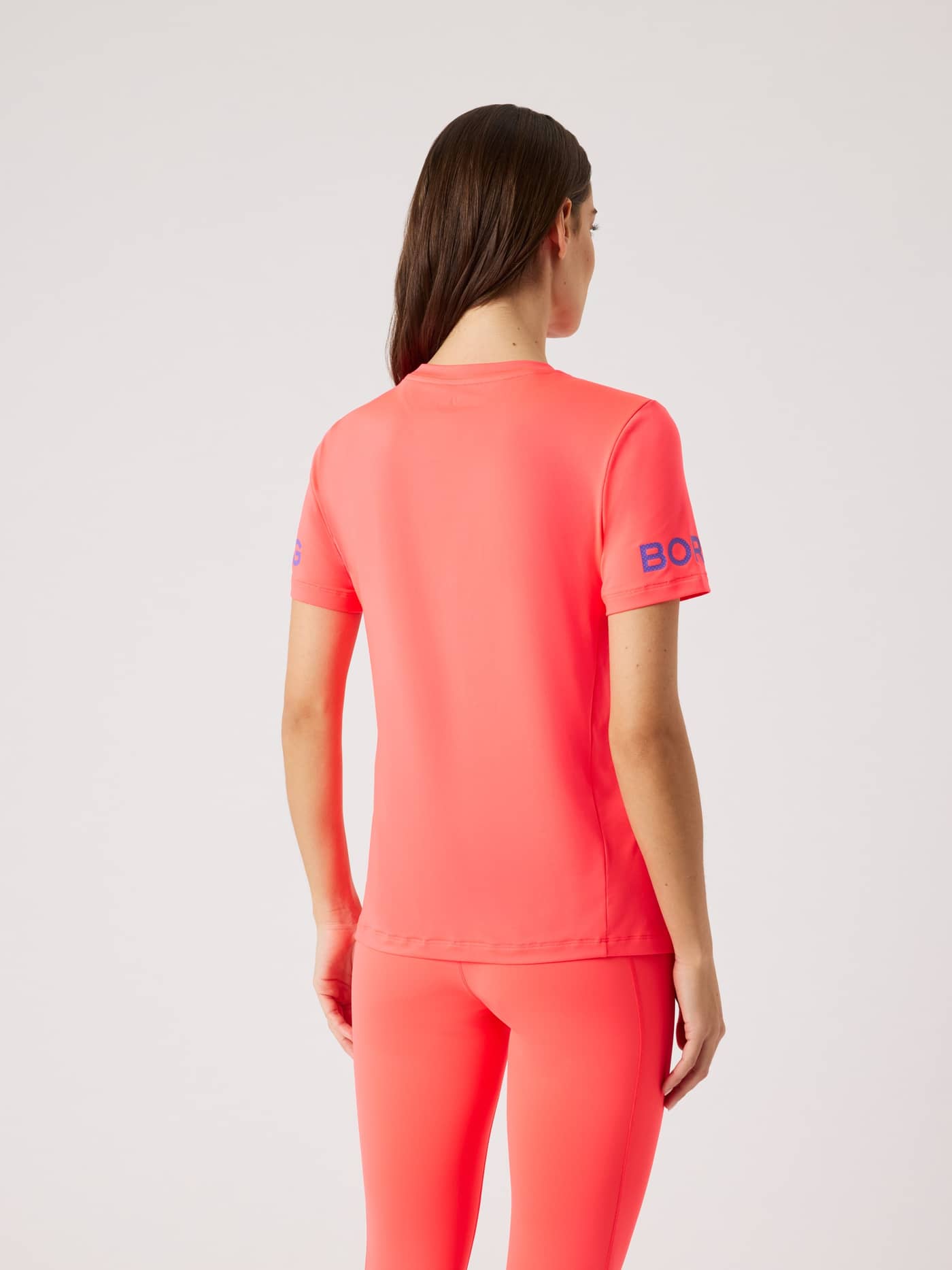 Back view of a woman wearing the regular fit Björn Borg Borg T-Shirt in Diva Pink (Pink) with blue sleeve logos for training. - Image 3