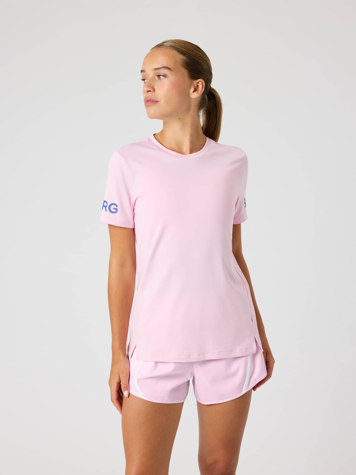 Vorderansicht eines Models im Borg T-Shirt in Pink Lady (Pink), ein recyceltes Regular-Fit-Trainingstop mit blauen Logos. - Image 1