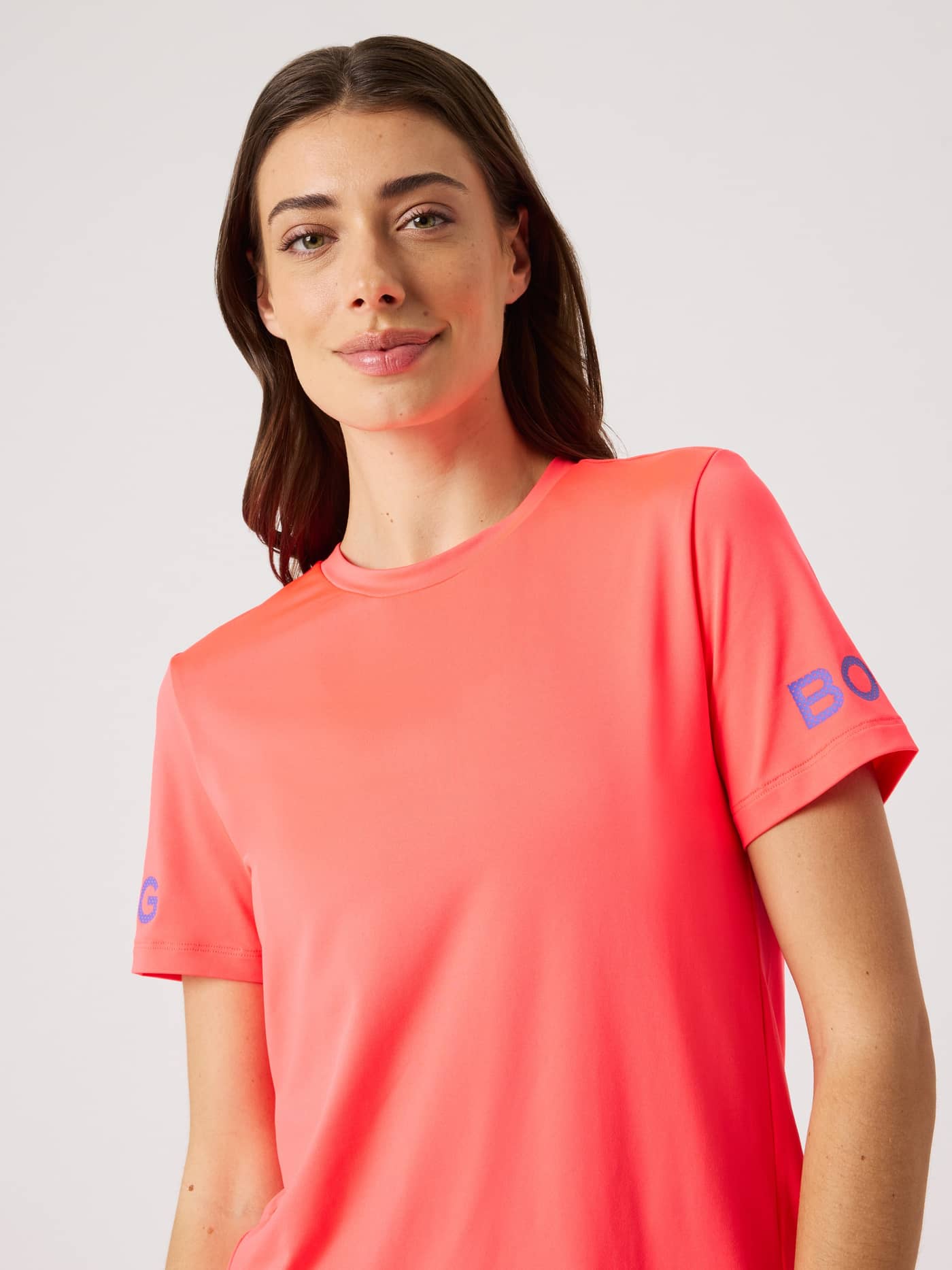 Front view of a woman in the Diva Pink (Pink) Borg T-Shirt, a regular fit training top with side slits and blue logos. - Image 6