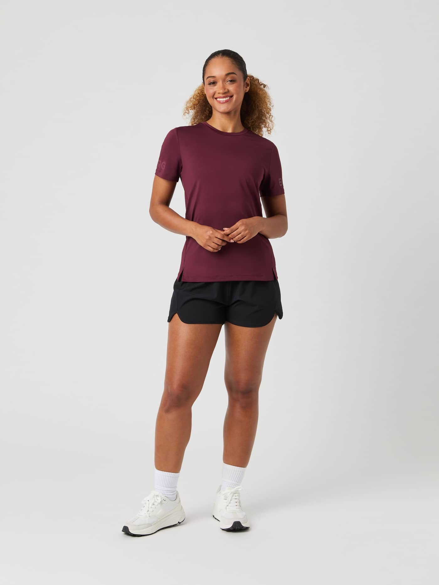 Full-length shot of a woman wearing the Björn Borg Borg T-Shirt in Port Royale, black shorts, and white sneakers. - Image 3