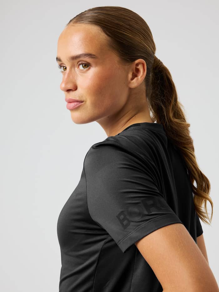 Zijaanzicht van het Borg T-Shirt in Black Beauty (Zwart) met een tonaal mouwlogo voor training en tennis.
