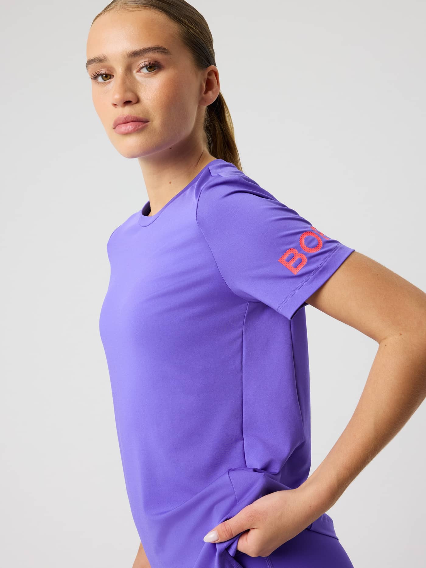 Borg T-shirt i Simply Purple (Lila) sedd från sidan, träningstopp med regular fit och orange logotyp på ärmen. - Image 5