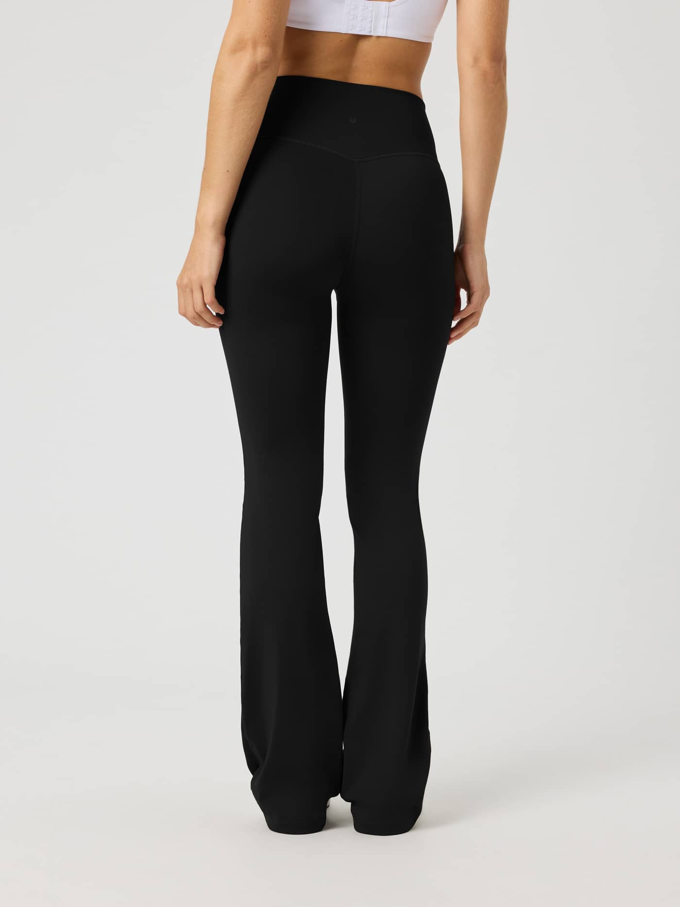 Back view of a woman in Borg Flare Tights Tall in Black Beauty (Black), showing the slim fit and flared legs for training. - Image 2